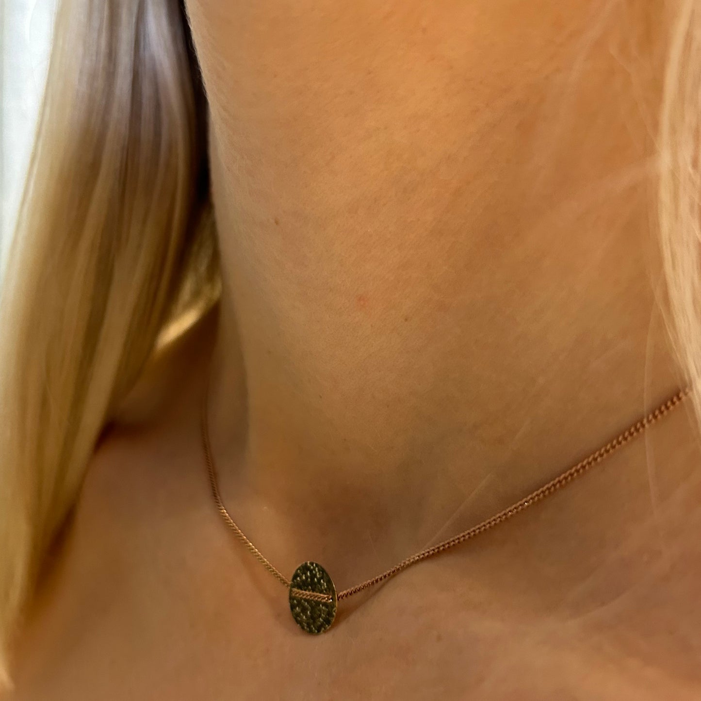 Rose gold chain choker with textured gold medallion threaded thru..